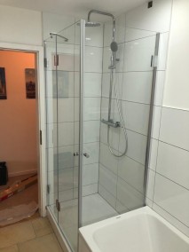 Dusche neben Badewanne AiW aus Glas auf Duschwanne in weiß gefliestem Badezimmer
