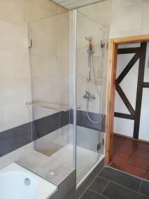 Duschkabine aus Glas neben Badewanne A2K om grau-weiß gefliestem Bad