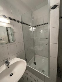 Nischentür Dusche A1N aus Glas auf Duschwanne in weiß gefliestem Badezimmer mit Wandbordüre
